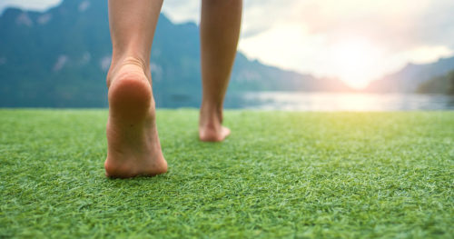 person's feet walking on the grass