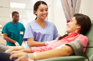 Nurse smiling at blood donor as donor gives blood