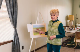 Dolores Ott, a stroke patient, poses next to her painting of an OSF LIfeFlight helicopter