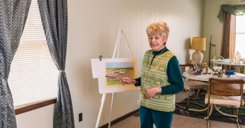 Dolores Ott, a stroke patient, poses next to her painting of an OSF LIfeFlight helicopter