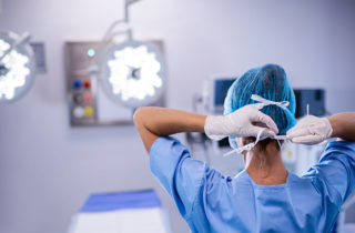 Surgical nurse putting on mask in an operating room