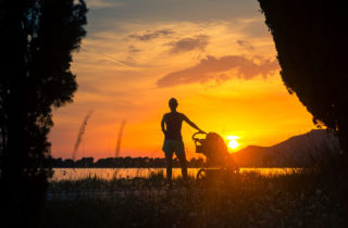 woman and child in stroller on a beach at sunset