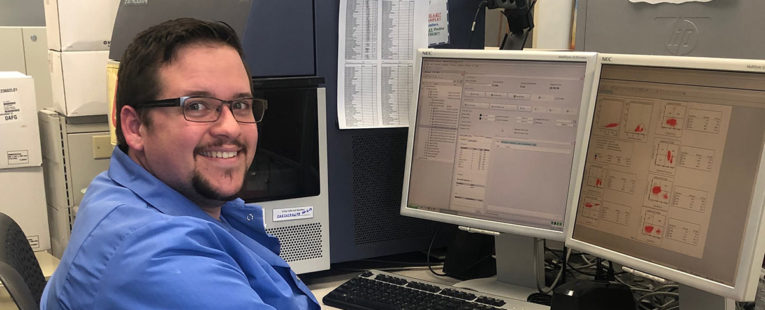 Joshua Barrett, Clinical Laboratory Scientist. He is working in our Flow Cytometry department, analyzing sample results and graphs.