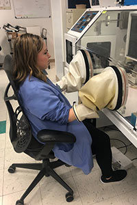 Jacquelyn Lynn, Clinical Laboratory Scientist. She is working in our Microbiology department, entering an anaerobic chamber for cultures.