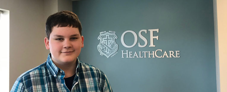 Kaleb stands by OSF HealthCare Children's Hospital sign