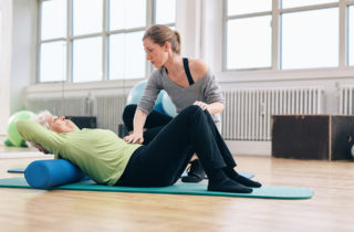 senior woman doing pelvic floor exercises in gym with trainer