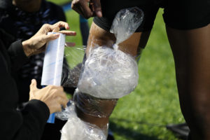 athletic trainer icing a football player's knee