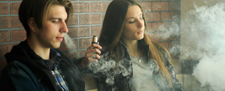 Teenage boy and girl vaping