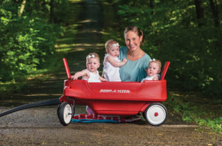 Colwell triplets and their mother in a wagon outdoors.