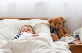 Male toddler with fever in bed