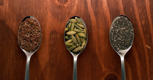 Flax seeds, pumpkin seeds, and chia seeds on spoons