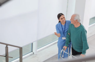Physical Therapist walking with senior male patient in hallway