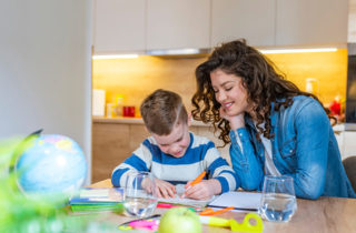 Young mother with son at kitchen table doing homework