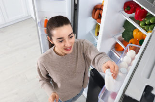 Young woman getting beverage out of refrigerator.