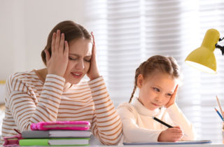 Stressed mother helping daughter with homework.