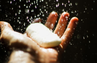 Man's hands holding a bar of soap getting wet.