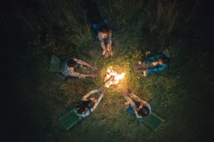 People socially distancing around a campfire.