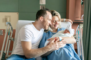 Newborn and parents in hospital bed.