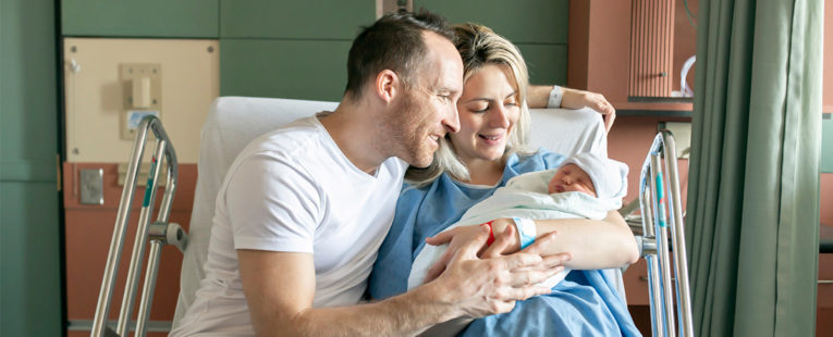 Newborn and parents in hospital bed.