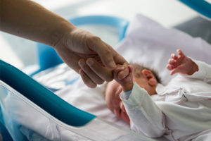 Newborn infant grabbing father's finger.