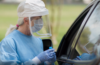 a nurse visits the side of a car during COVID-19 testing