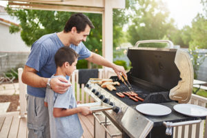 Father showing son safe grilling tecniques.