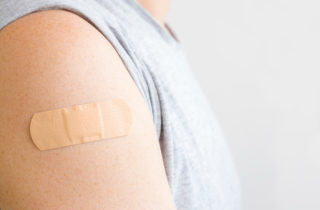 Young adult male with bandage on arm after receiving vaccine.