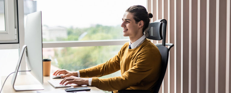 Young adult male professional in office performing computer programming.