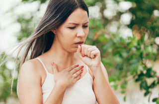woman coughing into her hand
