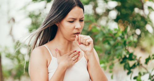 woman coughing into her hand