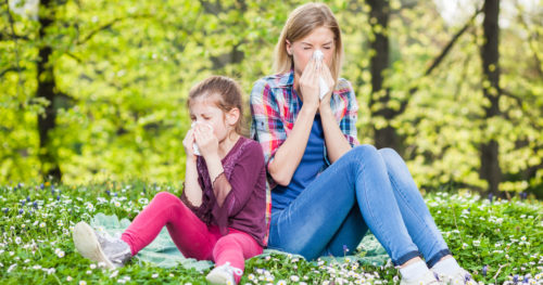 a small girl and a woman suffer with allergies outside