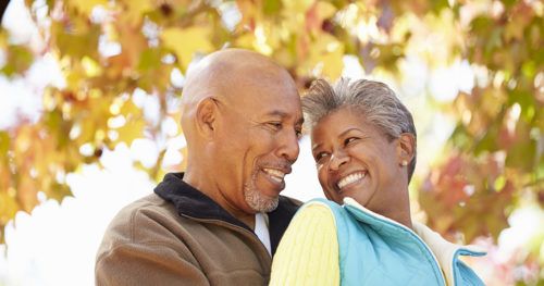 Active African-American senior couple in a warm embrace on an autumn day.
