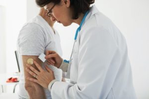 female physician places a nicotine patch on a male patient