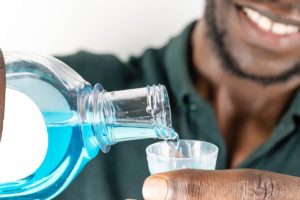 man smiles while pouring mouthwash into cup