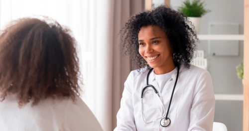 female doctor smiles as they meet with a female patient