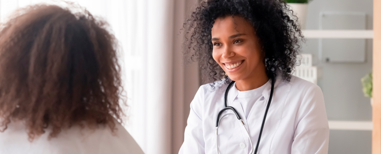 female doctor smiles as they meet with a female patient