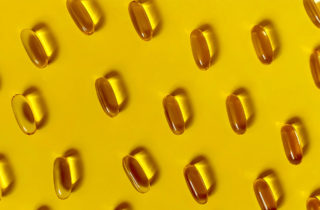 Vitamin D capsules on yellow background.