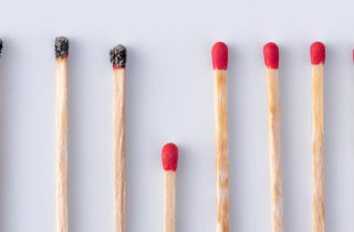 Line of burned matchsticks with several unburned matches to signify the COVID-19 death rate.
