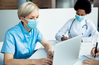 masked care team members work on laptops