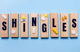 The word "shingles" is spelled out on wooden tiles with medicine placed on top.