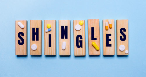 The word "shingles" is spelled out on wooden tiles with medicine placed on top.