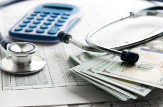 Medical expenses and paying for cancer treatment can be expensive. Image of a stethoscope, a bill, a calculator and cash.