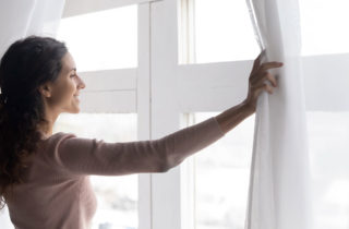 Woman cancer survivor looking hopeful out her living room window