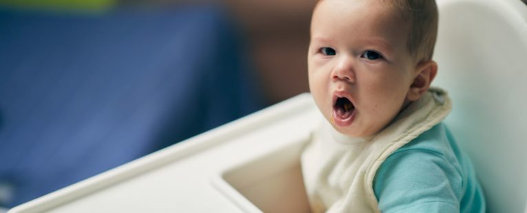 a coughing baby in highchair.