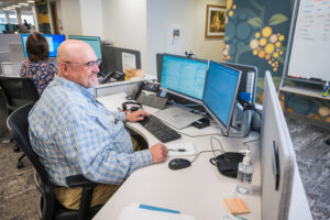 A man sits at his desk looking at two computer screens at the OnCall Contact Center.