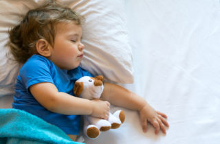 Young boy sleeping with stuffed animal.