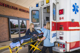 Man on stretcher being loaded into an ambulance by two women