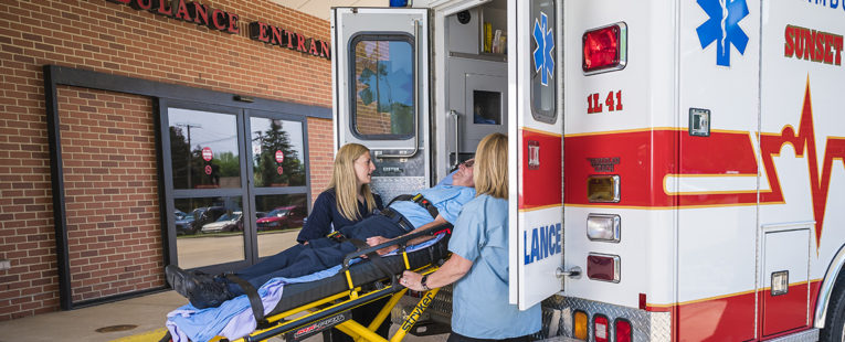 Man on stretcher being loaded into an ambulance by two women