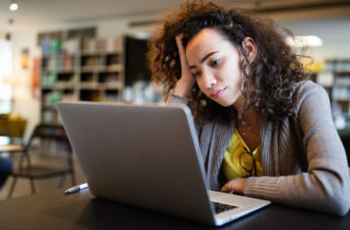 Woman with ADHD looks at her laptop with a pensive expression.