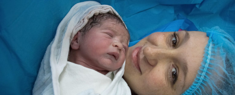 A mother and her baby smile after a c-section.